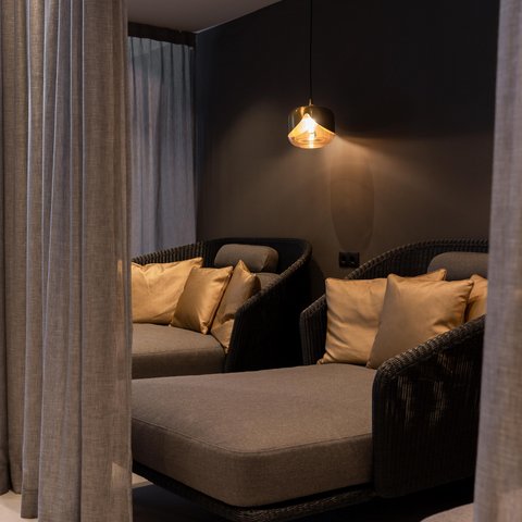 Bilder aus der Sportalm Gemütliche Sitzecke mit grauer Polsterung, goldenen Kissen und hängender Lampe