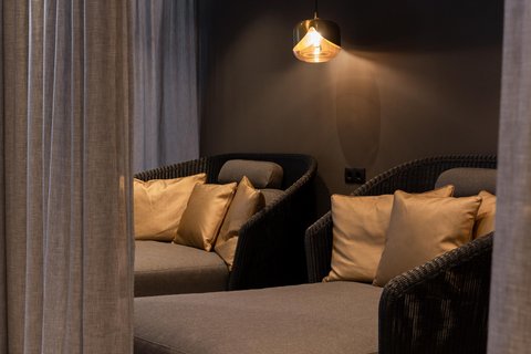 Bilder aus der Sportalm Gemütliche Sitzecke mit grauer Polsterung, goldenen Kissen und hängender Lampe