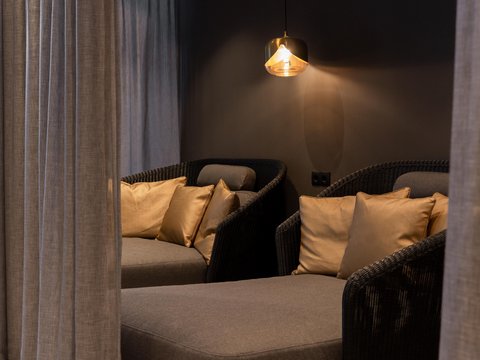 Bilder aus der Sportalm Gemütliche Sitzecke mit grauer Polsterung, goldenen Kissen und hängender Lampe