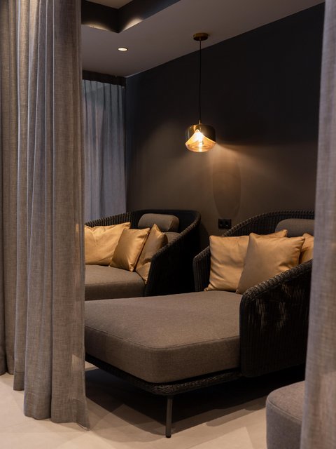 Bilder aus der Sportalm Gemütliche Sitzecke mit grauer Polsterung, goldenen Kissen und hängender Lampe