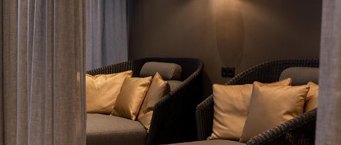 Bilder aus der Sportalm Gemütliche Sitzecke mit grauer Polsterung, goldenen Kissen und hängender Lampe