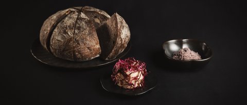 Bilder aus der Sportalm Rundes Brot auf Teller mit Butter und Salz vor dunklem Hintergrund