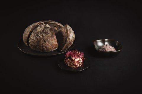 Pictures from Sportalm Round bread on plate with butter and salt against dark background