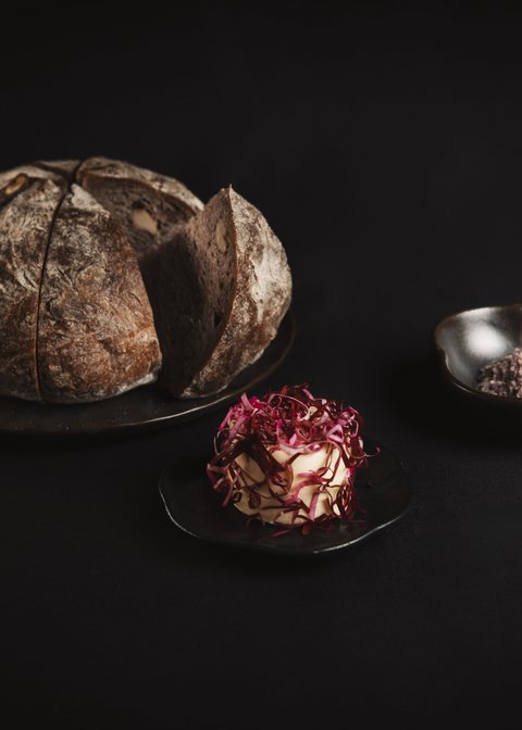 Pictures from Sportalm Round bread on plate with butter and salt against dark background