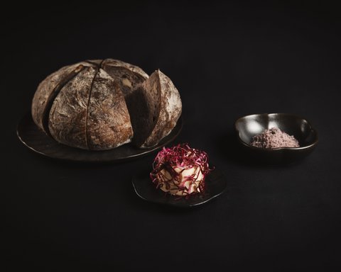 Pictures from Sportalm Round bread on plate with butter and salt against dark background