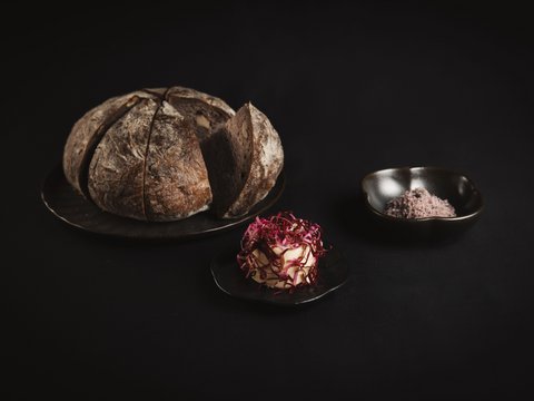 Unser Restaurant im Pitztal Rundes Brot auf Teller mit Butter und Salz vor dunklem Hintergrund
