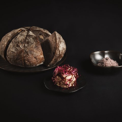 Pictures from Sportalm Round bread on plate with butter and salt against dark background