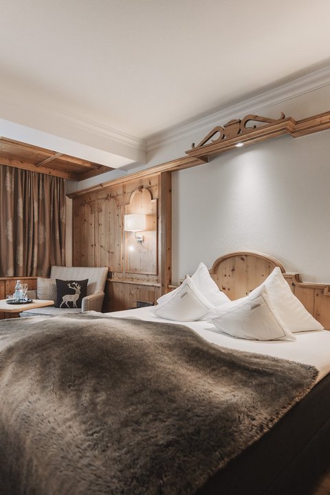 Bilder aus der Sportalm Gemütliches Hotelzimmer mit Holzverkleidung und großem Bett