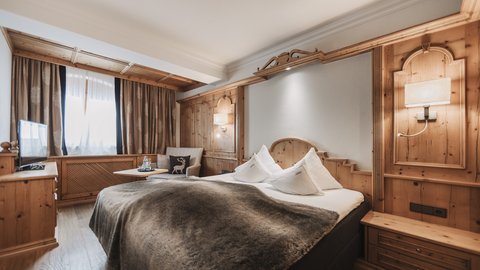 Bilder aus der Sportalm Gemütliches Hotelzimmer mit Holzverkleidung und großem Bett