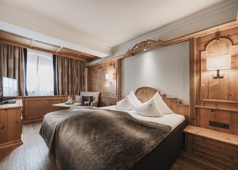 Bilder aus der Sportalm Gemütliches Hotelzimmer mit Holzverkleidung und großem Bett
