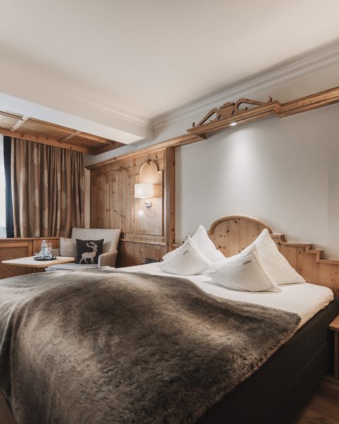 Bilder aus der Sportalm Gemütliches Hotelzimmer mit Holzverkleidung und großem Bett