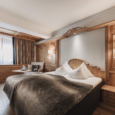 Bilder aus der Sportalm Gemütliches Hotelzimmer mit Holzverkleidung und großem Bett