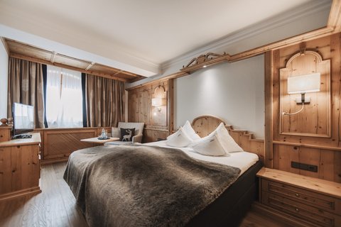 Bilder aus der Sportalm Gemütliches Hotelzimmer mit Holzverkleidung und großem Bett