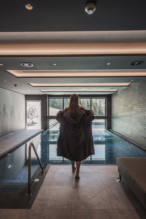 Pictures from Sportalm Woman in bathrobe by indoor pool with panoramic window and mountain view