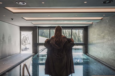 Pictures from Sportalm Woman in bathrobe by indoor pool with panoramic window and mountain view
