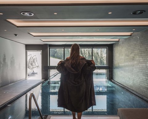 Pictures from Sportalm Woman in bathrobe by indoor pool with panoramic window and mountain view