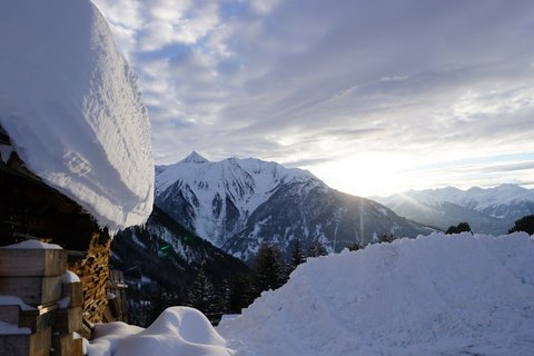 Bilder aus der Sportalm Verschneite Hütte und schneebedeckte Berge bei Sonnenuntergang