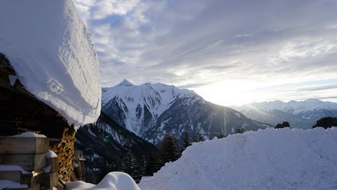 Bilder aus der Sportalm Verschneite Hütte und schneebedeckte Berge bei Sonnenuntergang