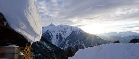 Bilder aus der Sportalm Verschneite Hütte und schneebedeckte Berge bei Sonnenuntergang
