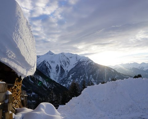 Bilder aus der Sportalm Verschneite Hütte und schneebedeckte Berge bei Sonnenuntergang