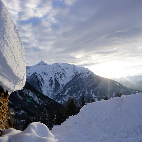 Bilder aus der Sportalm Verschneite Hütte und schneebedeckte Berge bei Sonnenuntergang