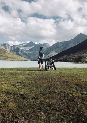Nicht irgendein Pitztal-Resort: Alpine Resort Sportalm! Radfahrer blickt auf Bergsee und Alpen unter bewölktem Himmel