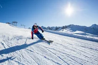 Skifahrer fährt schnell auf sonniger Piste in den Bergen