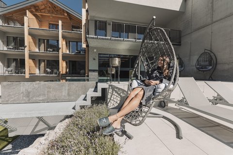 Pictures from Sportalm Woman relaxing in a hanging chair on terrace with modern building background