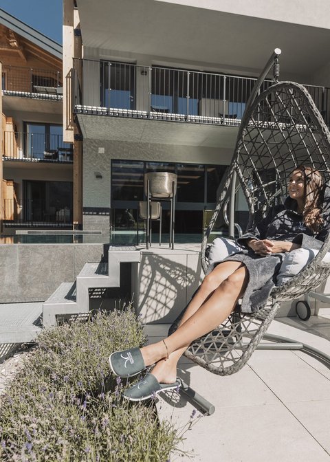 Pictures from Sportalm Woman relaxing in a hanging chair on terrace with modern building background