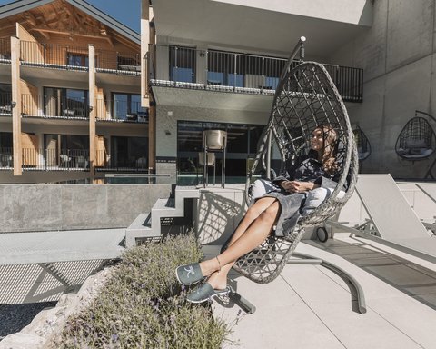 Pictures from Sportalm Woman relaxing in a hanging chair on terrace with modern building background