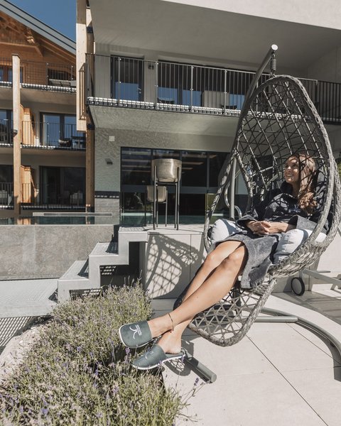 Pictures from Sportalm Woman relaxing in a hanging chair on terrace with modern building background