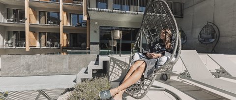 Bilder aus der Sportalm Frau entspannt in einem Hängesessel auf einer Terrasse mit moderner Architektur