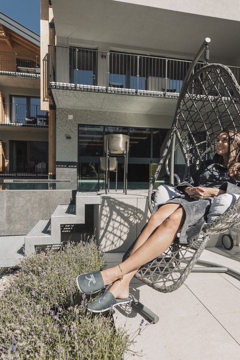 Bilder aus der Sportalm Frau entspannt in einem Hängesessel auf einer Terrasse mit moderner Architektur