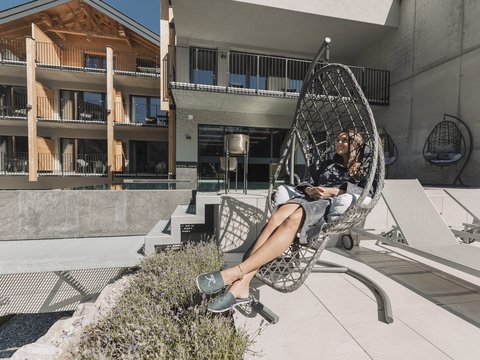 Bilder aus der Sportalm Frau entspannt in einem Hängesessel auf einer Terrasse mit moderner Architektur