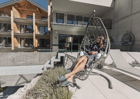 Pictures from Sportalm Woman relaxing in a hanging chair on terrace with modern building background
