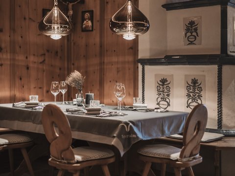 Unser Restaurant im Pitztal Rustikaler Esstisch mit Holzstühlen und Keramikofen in warmem Raum