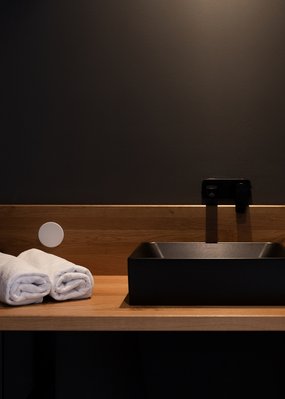 Wohltuende Wellnessbehandlungen Moderner Waschbeckenbereich mit schwarzem Becken und zwei weißen Handtüchern