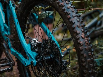 „Nuigkeiten“ aus der Sportalm Nahaufnahme eines verschmutzten blauen Mountainbike-Hinterrads mit grobem Reifenprofil