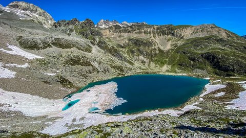 Pictures from Sportalm Mountain lake with melting snow and rocky terrain under clear blue sky