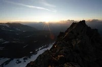 Sunrise over snowy mountains with rocky peak in the foreground