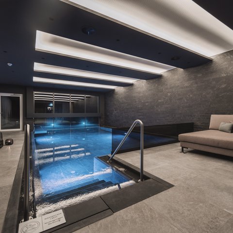 Bilder aus der Sportalm Modernes Hallenbad mit Sitzbereich und indirekter Deckenbeleuchtung