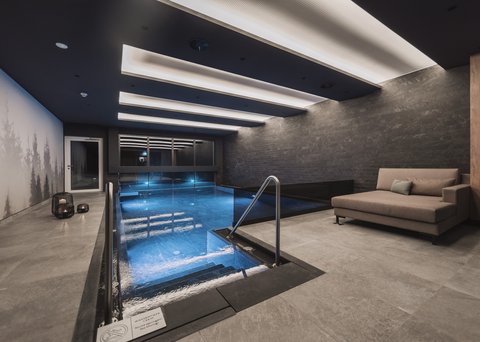 Bilder aus der Sportalm Modernes Hallenbad mit Sitzbereich und indirekter Deckenbeleuchtung