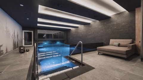 Pictures from Sportalm Modern indoor pool with seating area and indirect ceiling lighting
