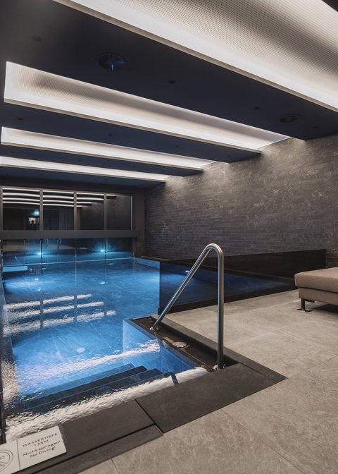 Pictures from Sportalm Modern indoor pool with seating area and indirect ceiling lighting