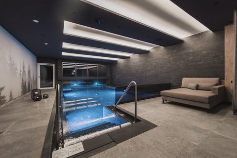 Pictures from Sportalm Modern indoor pool with seating area and indirect ceiling lighting