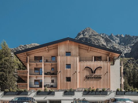 Bilder aus der Sportalm Alpenresort Sportalm mit Bergen im Hintergrund und geparkten Autos