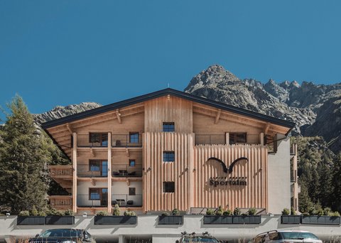 Bilder aus der Sportalm Alpenresort Sportalm mit Bergen im Hintergrund und geparkten Autos