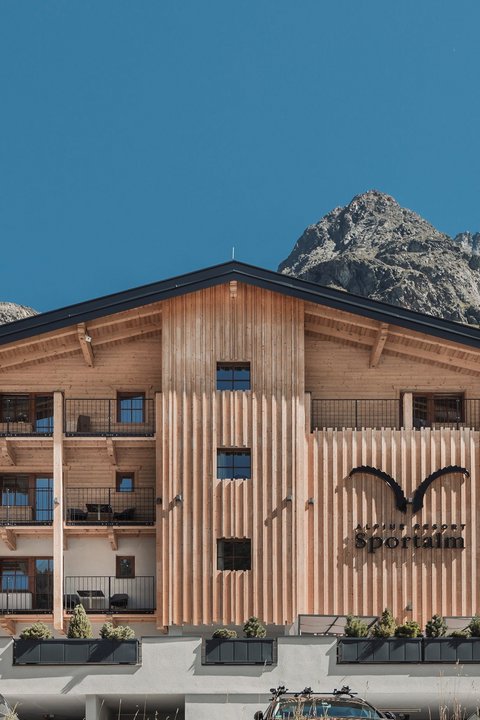 Bilder aus der Sportalm Alpenresort Sportalm mit Bergen im Hintergrund und geparkten Autos