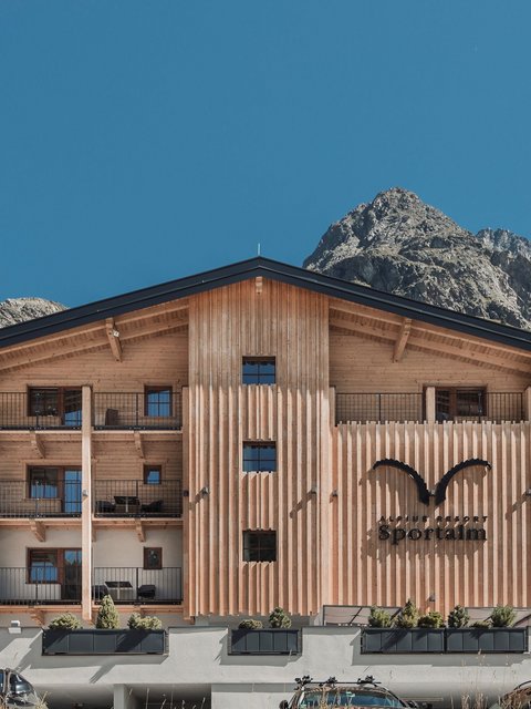 Bilder aus der Sportalm Alpenresort Sportalm mit Bergen im Hintergrund und geparkten Autos