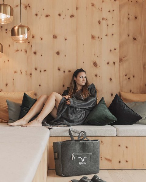 Pictures from Sportalm Woman relaxing on wooden couch with pillows and hanging lamps